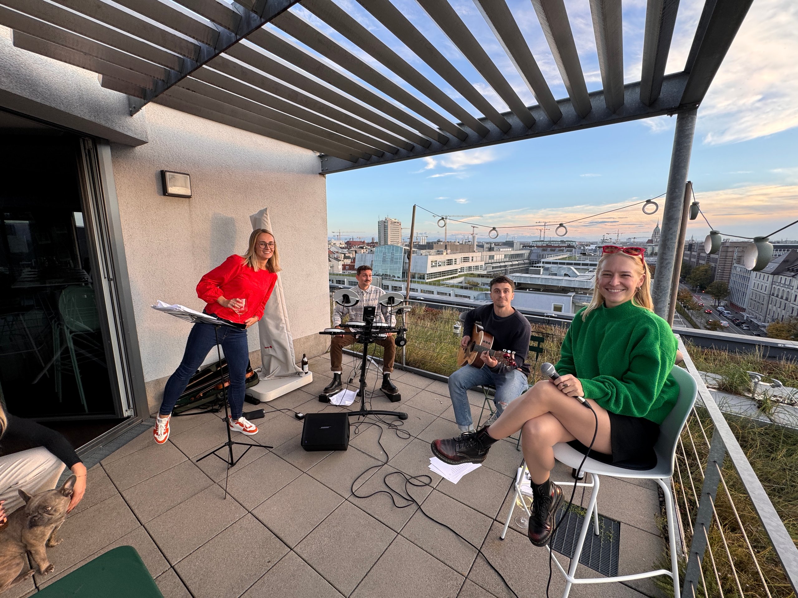 Group of people playing music on a rooftop with city views.