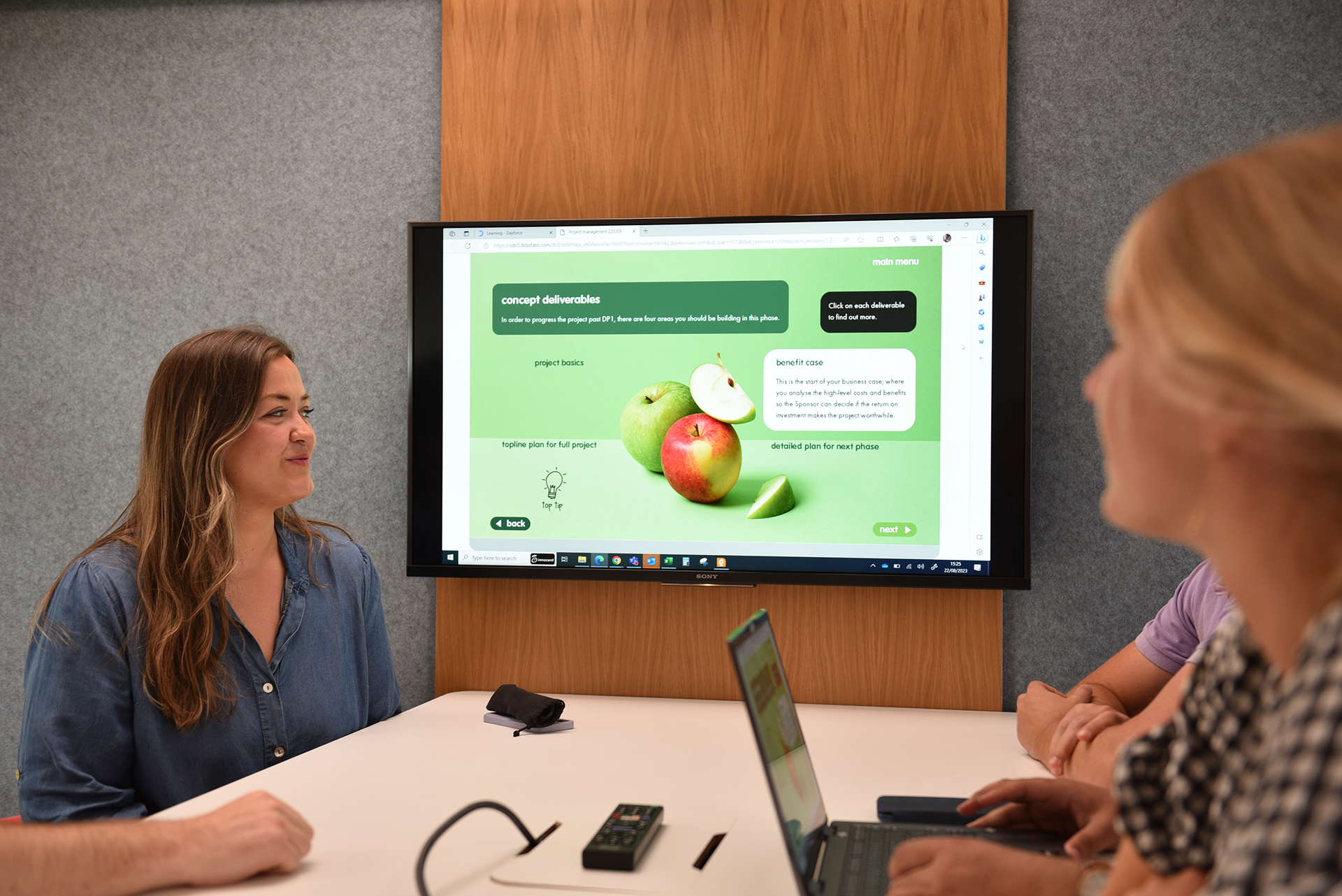 People at a meeting looking at a screen with project details.