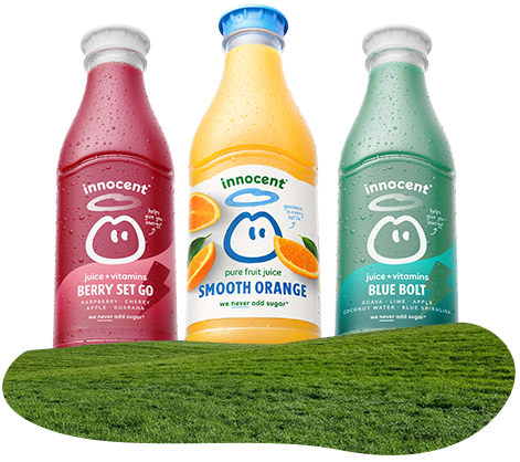 Three Innocent smoothie bottles on a grassy surface.